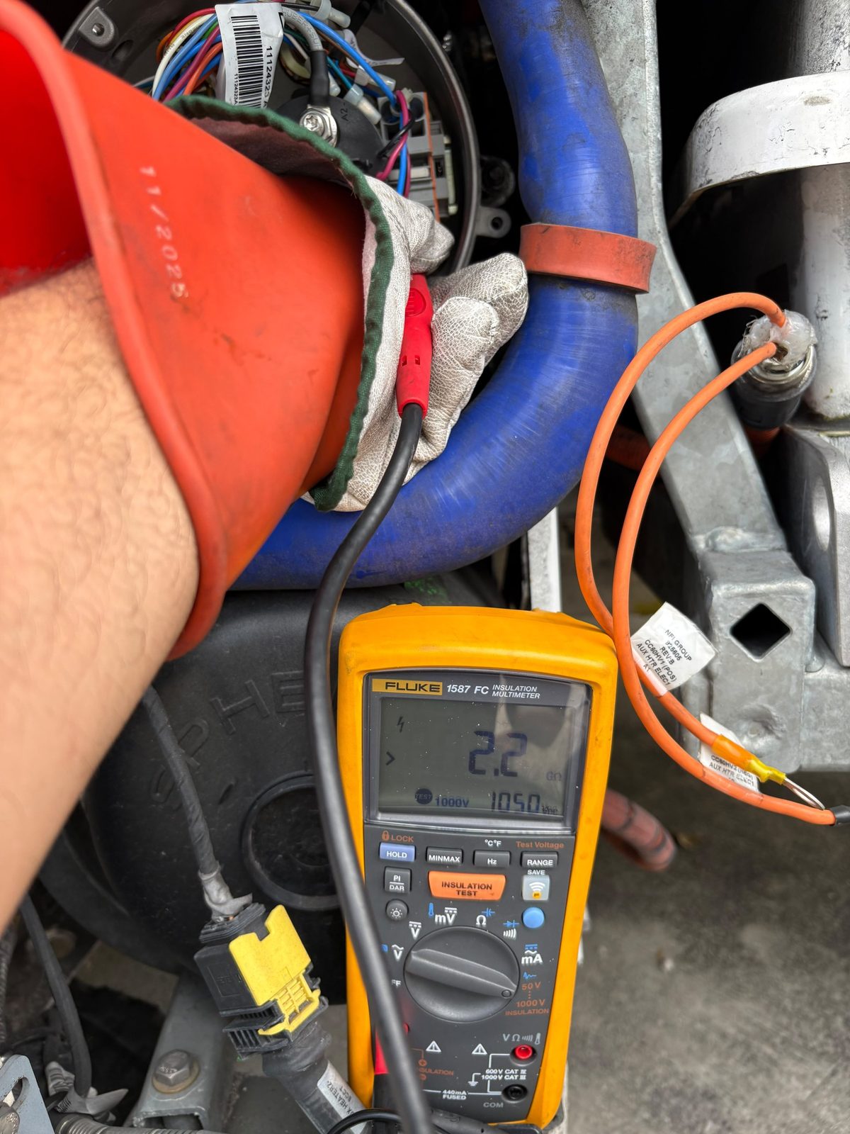 Technician in rated high voltage gloves testing insulation with a Fluke 1587 FC reading 2.2 gigaohms at 1000 volts