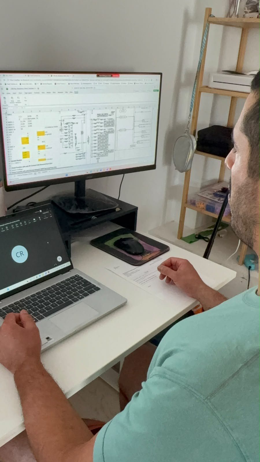 Sebastian at his desk diagnosing a vehicle remotely, with his diagnostic sheet and a wiring schematic on screen and the on-site tech on a video call